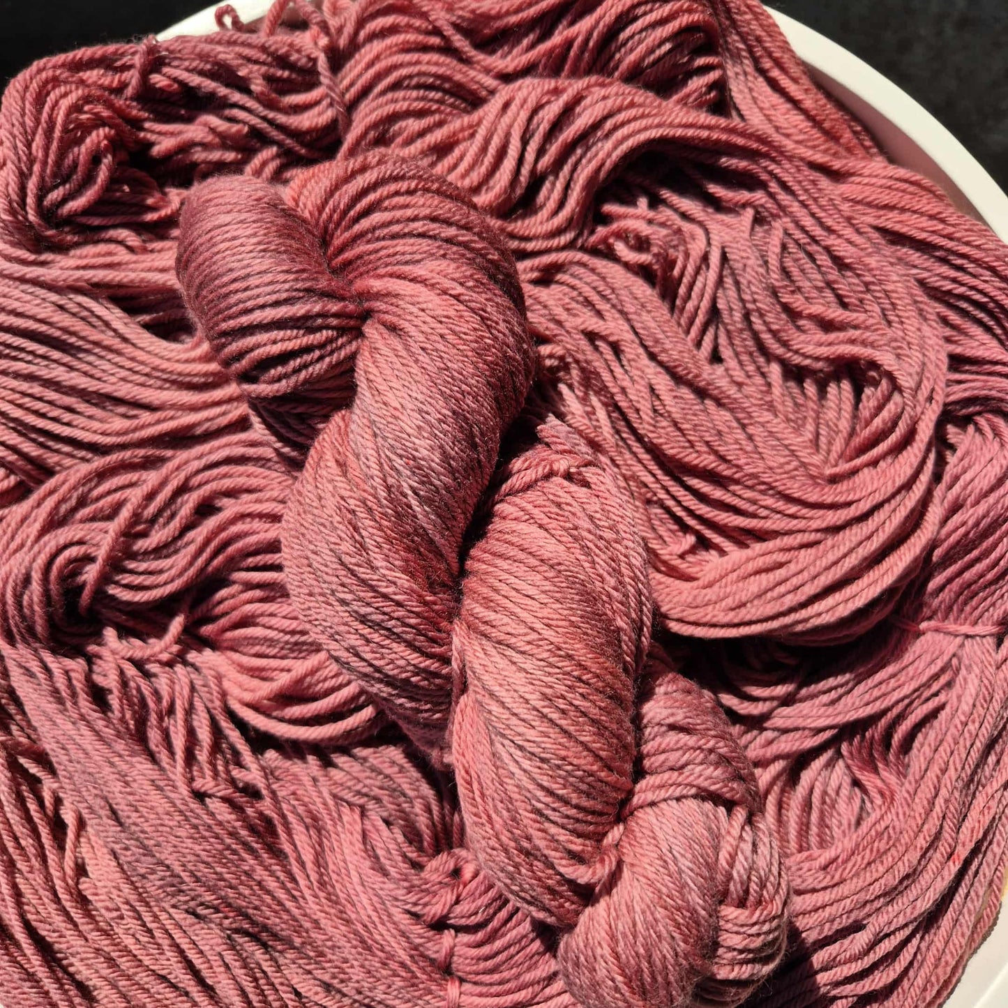 Red wine coloured yarn on a white surface with a dark background