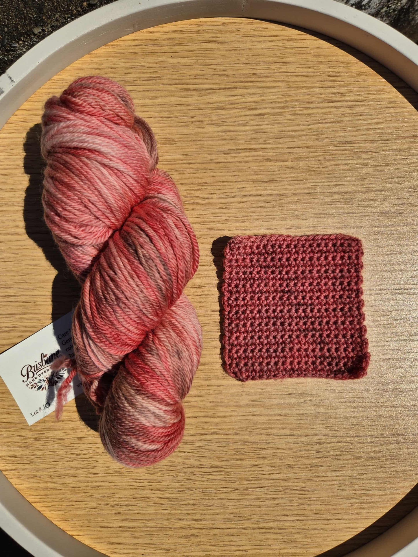 Red skein of yarn and a red crochet swatch on a wooden surface