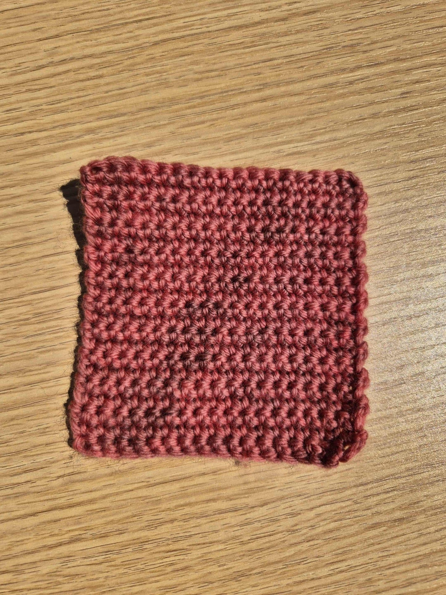 Red crochet square on a wooden surface