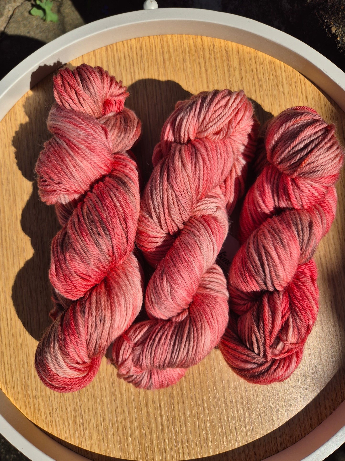 Red skeins of yarn on a wooden surface.