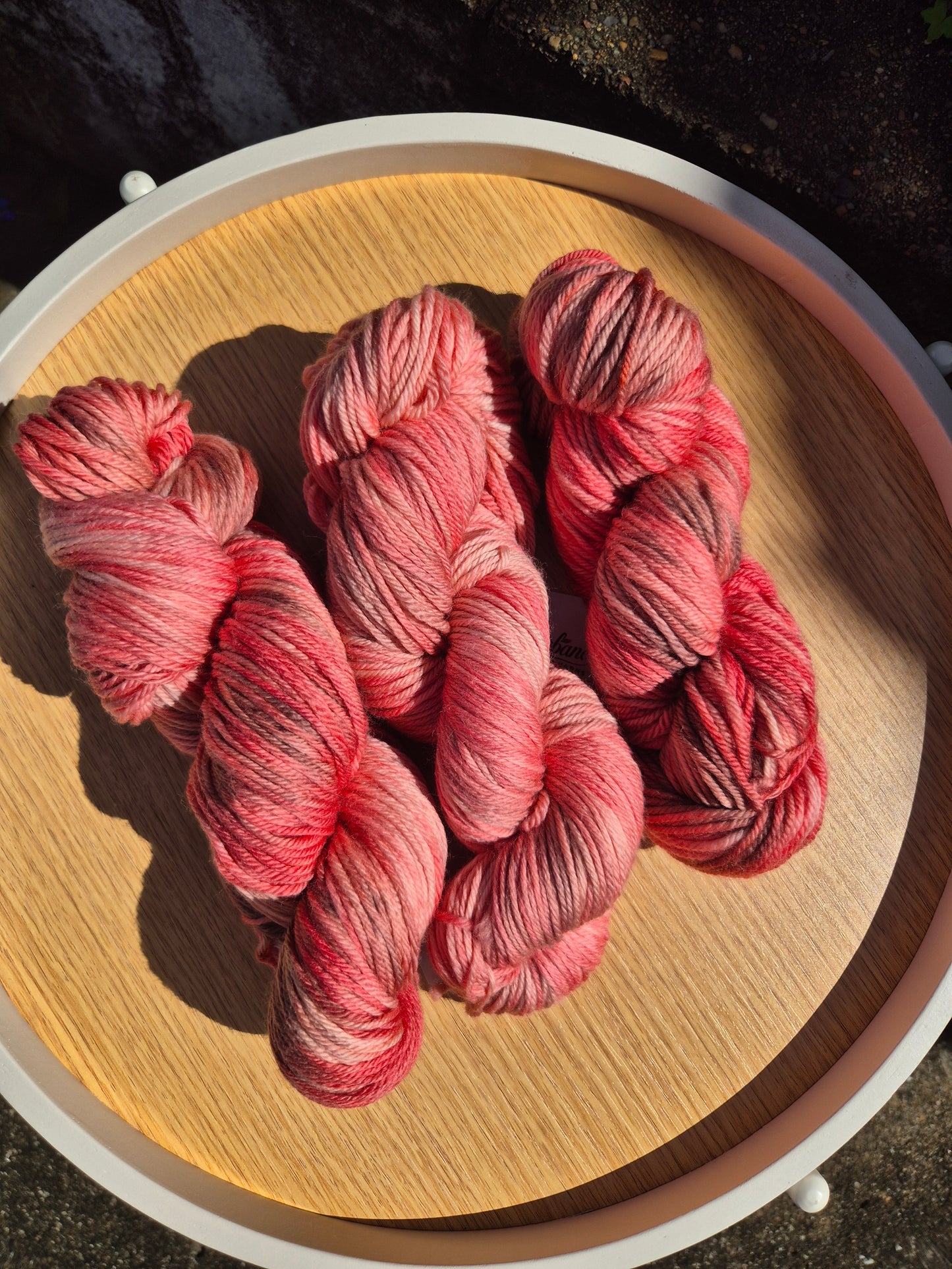 Pink and brown skeins of yarn on a wooden surface.