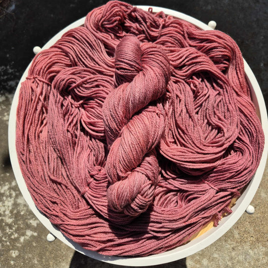 Red wine coloured yarn skein on a white board with a dark background