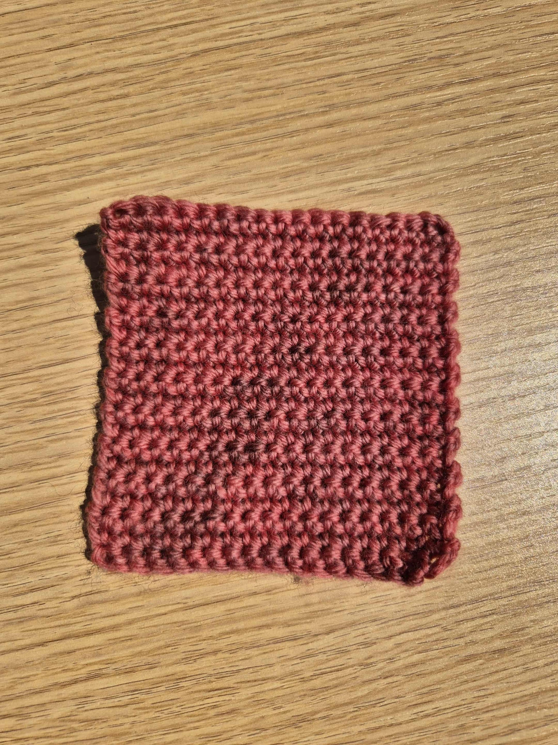 Red crochet square on a wooden surface